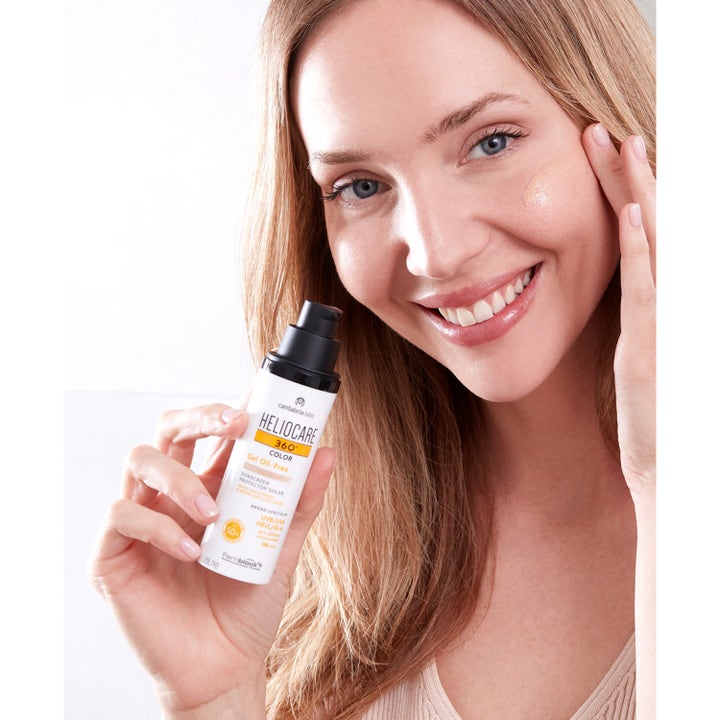 Heliocare Gel Oil-Free SPF 50+ Beige 50 ml aurinkovoide. Nainen levittää sävyttävää geeliä poskelleen.