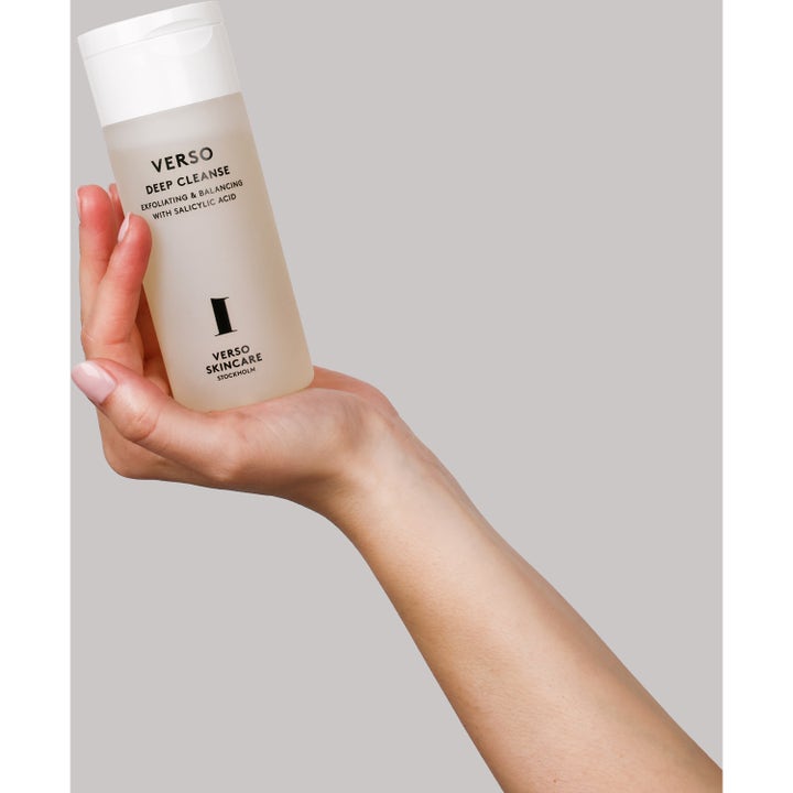 Verso N°1 Deep Cleanse 150 ml kuoriva puhdistusaine kädessä vaaleassa muovipullossa.