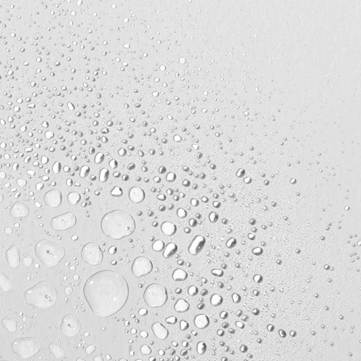 Dermalogica Multi-Active Toner Duo kosteuttava kasvovesi ja kirkkaita vesipisaroita vaalealla pinnalla.