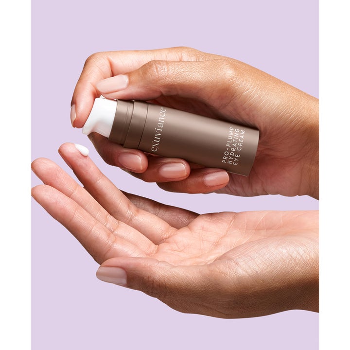 Exuviance Pro-Plump Hydrating Eye Cream 15 g kosteuttava ögonkräm kädessä, jossa on valkoista voidetta.