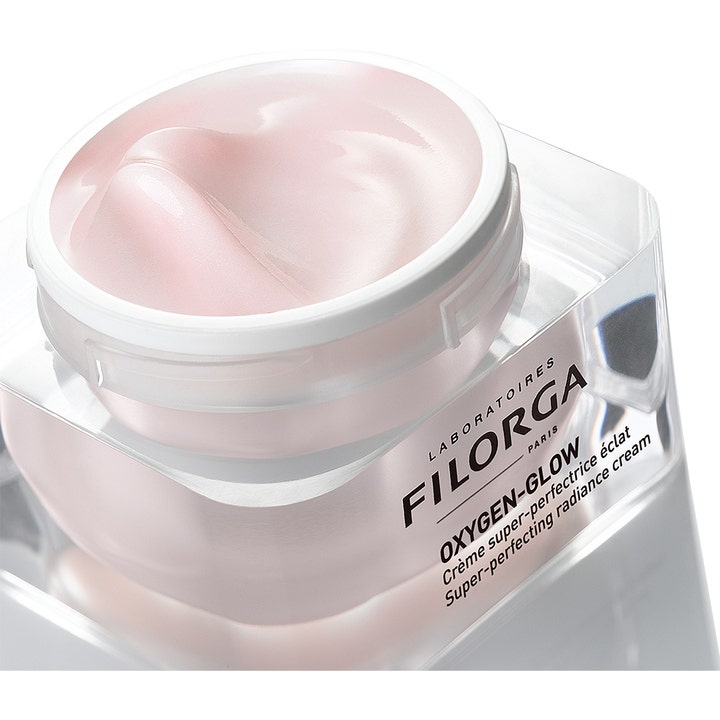 Filorga Oxygen-Glow Cream 50 ml kirkastava päivävoide, jonka vaaleanpunainen helmiäishohtoinen koostumus näkyy avatussa purkissa.