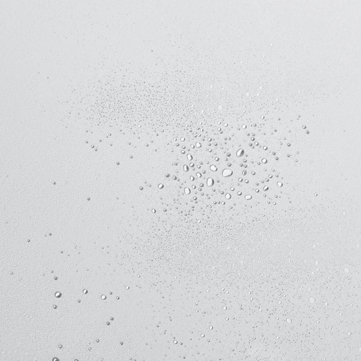 Rauhoittava Dermalogica UltraCalming Mist 177 ml kasvovesi kirkkaina vesipisaroina vaalealla pinnalla