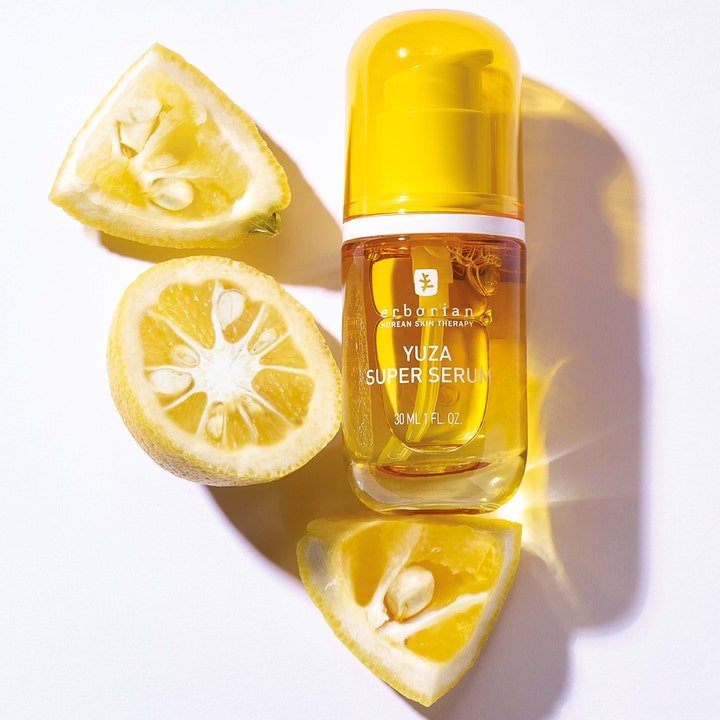 Erborian Yuza Super Serum 30 ml kirkastava kasvoseerumi keltaisessa pullossa tuoreiden yuzu-hedelmien ympäröimänä.