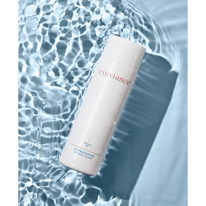 Exuviance HydraSoothe Refresh Toner 200 ml rauhoittava kasvovesi valkoisessa pullossa aaltoilevan veden päällä.