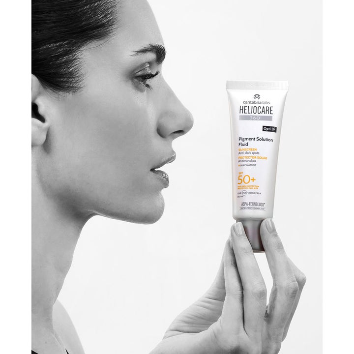 Heliocare Pigment Solution Fluid SPF 50+ 50 ml aurinkovoide pigmenttiläiskiä vastaan naisen pitelemässä tuubissa.