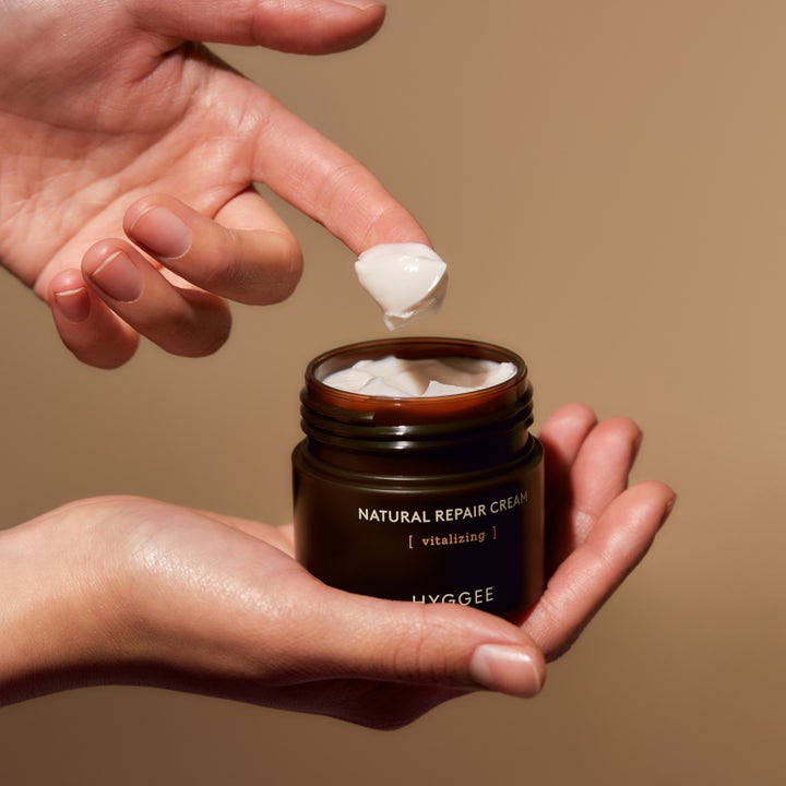 Hyggee Natural Repair Cream 50 ml uudistava päivävoide jonka täyteläistä valkoista koostumusta nostetaan sormella purkista.
