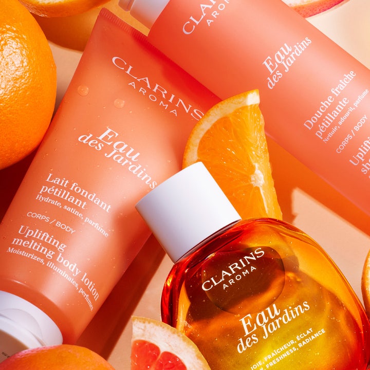 Clarins Eau des Jardins 200 ml heleyttävä vartalovoide oranssissa tuubissa tuoreiden sitrushedelmien ympäröimänä.