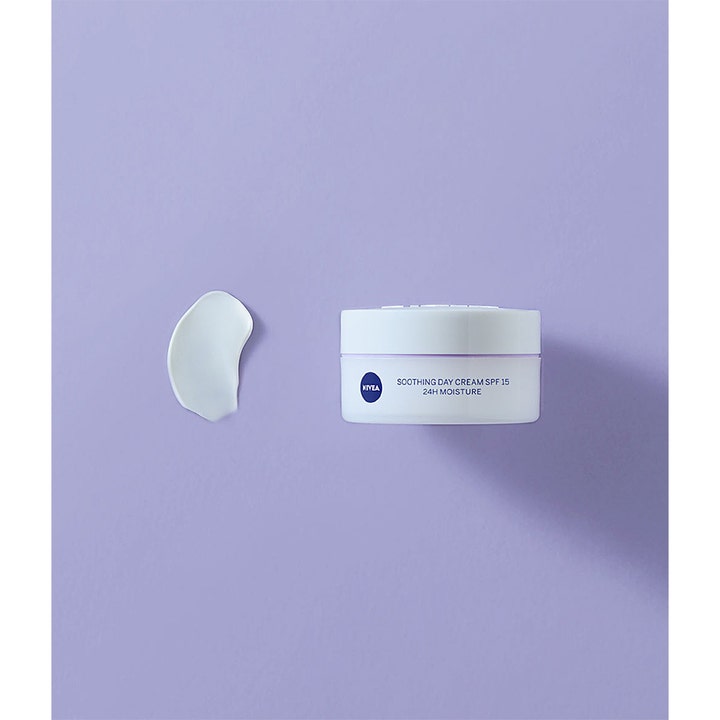 NIVEA Soothing Day Cream SPF15 50 ml rauhoittava päivävoide valkoisessa purkissa ja pehmeä voidepisara lilalla pohjalla