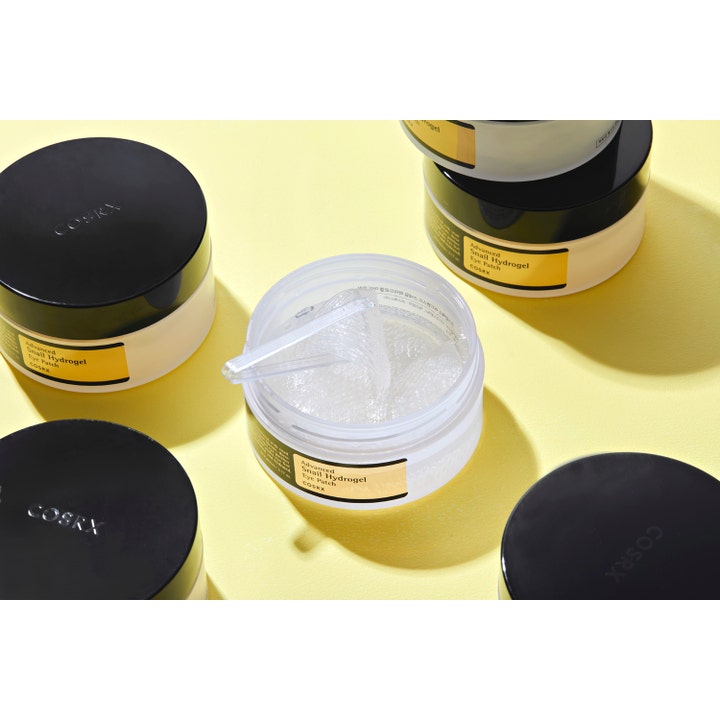 COSRX Advanced Snail Hydrogel Eye Patches 60 kpl kosteuttavat silmänympäryslaput avatussa purkissa kirkkaalla tekstuurilla