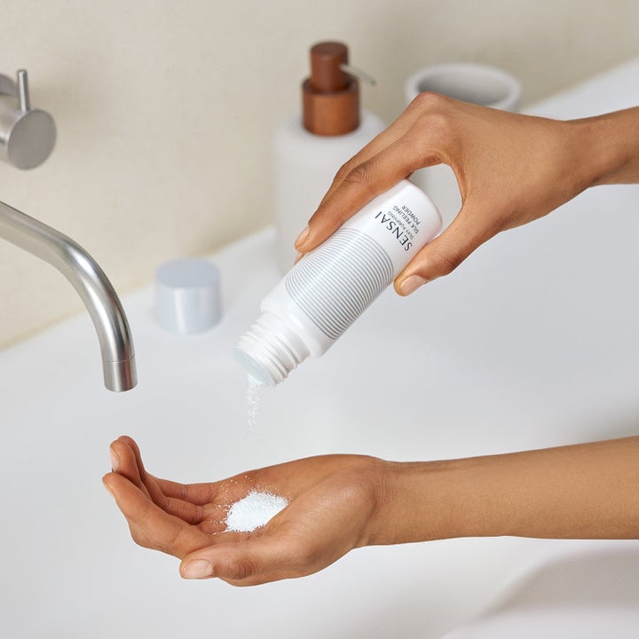 Sensai Silky Purifying Silk Peeling Powder syväpuhdistava kuorintajauhe annosteltuna kädelle valkoisesta pullosta