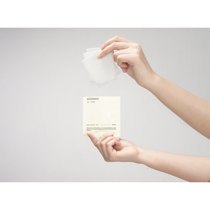 Mixsoon Soybean Milk Pad Toner Pad 30 kpl kosteuttava sheet mask ja kädet pitelemässä valkoisia hoitolappuja