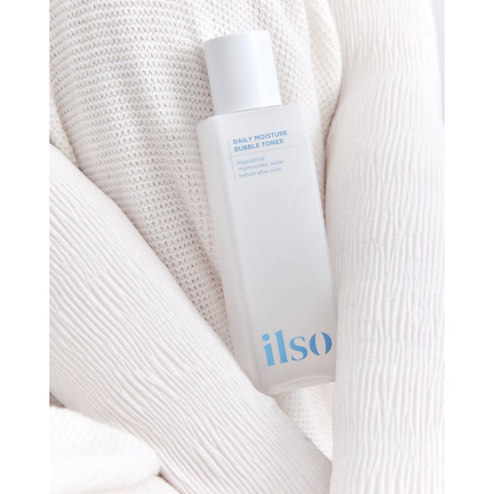 Ilso Daily Moisture Bubble Toner 150 ml kosteuttava kasvovesi valkoisessa pullossa vaalean neuleen päällä.
