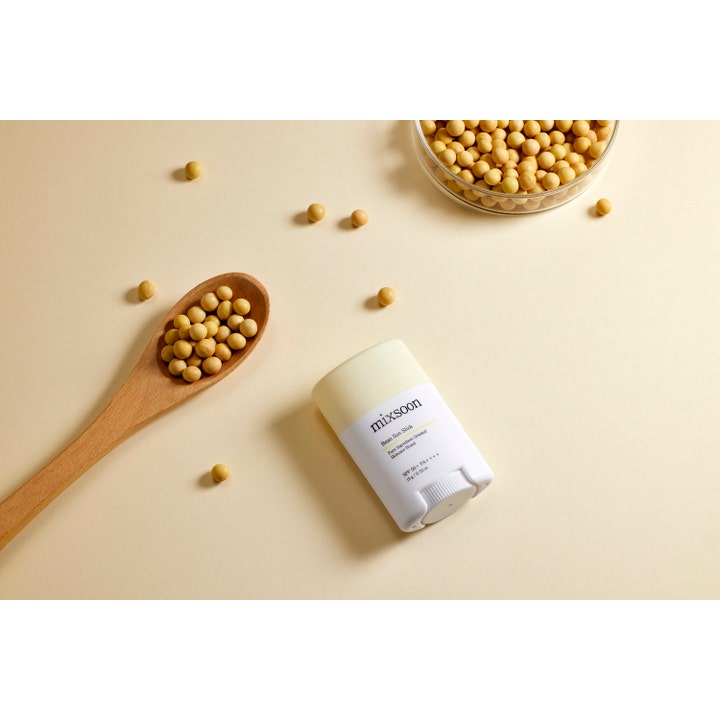 Mixsoon Bean Sun Stick 15 g suojaava aurinkosuojapuikko valkoisessa hylsyssä soijapapujen ja puulusikan ympäröimänä.