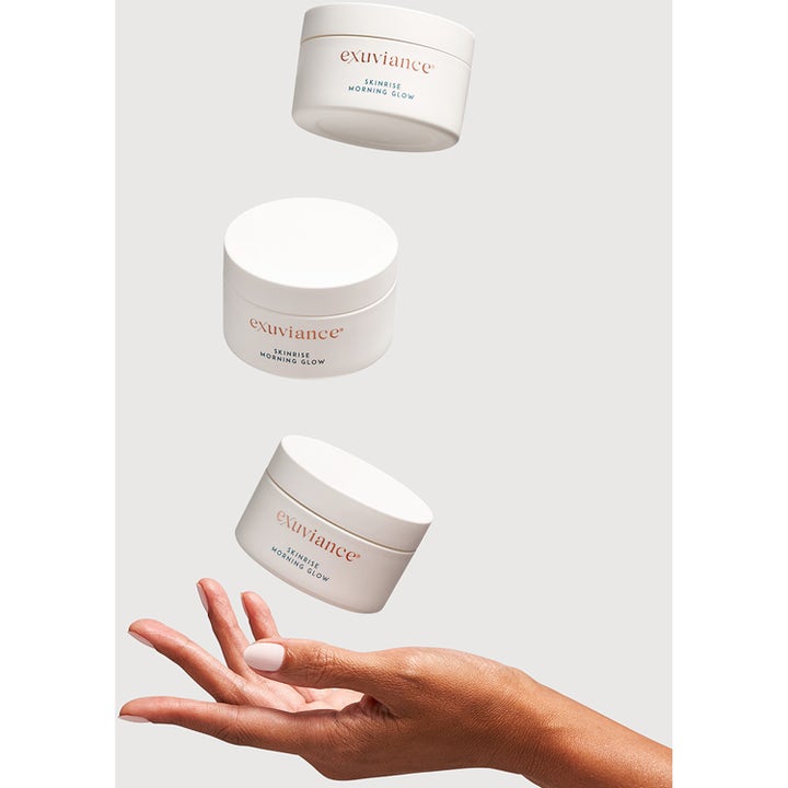 Exuviance SkinRise Morning Glow 36 kpl heleyttävä seerumi kolme valkoista purkkia ilmassa kämmenen yllä