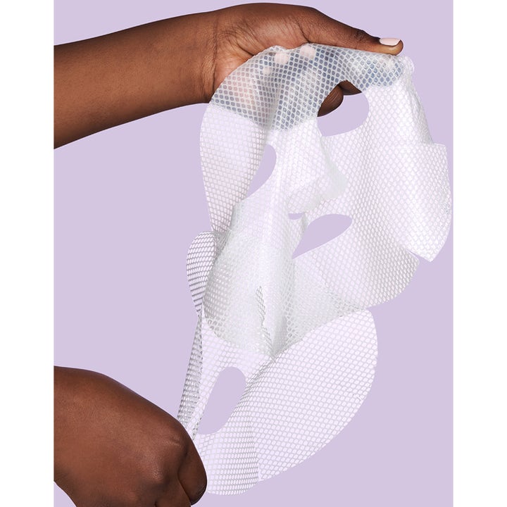 Exuviance Pick-Me-Up Plumping Mask 20 g täyteläistävä kangasnaamio valkoisella verkkokuviolla liilalla taustalla.