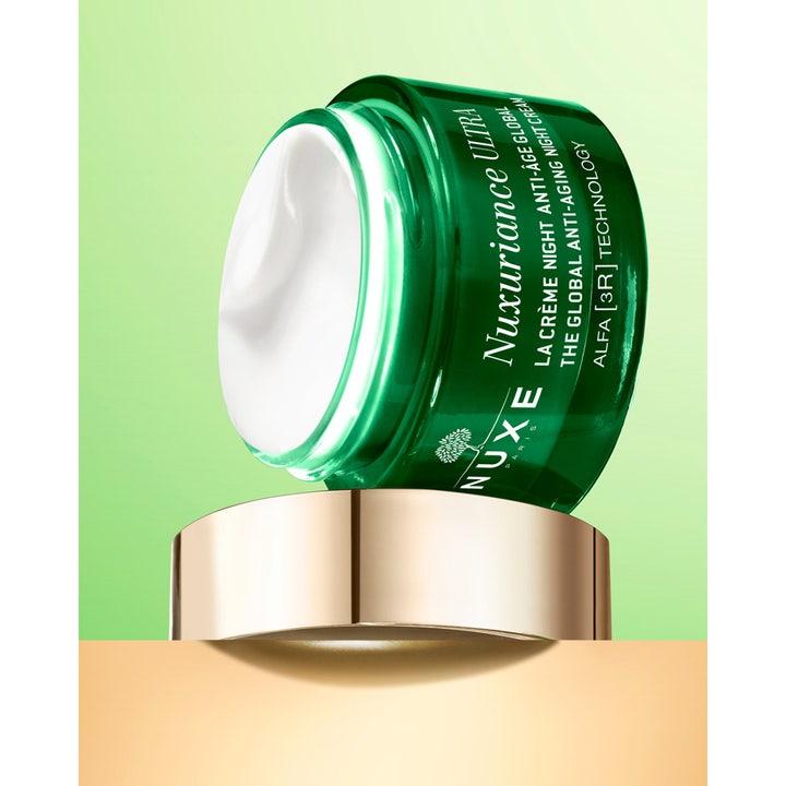 Nuxe Nuxuriance Gold Night Balm 184 g uudistava yövoide vihreässä lasipurkissa, jossa on täyteläistä valkoista voidetta.