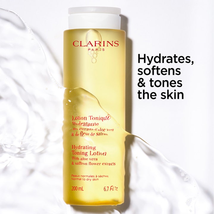 Clarins Hydrating Toning Lotion 200 ml kosteuttava kasvovesi keltaisessa pullossa raikkaiden vesiroiskeiden keskellä.