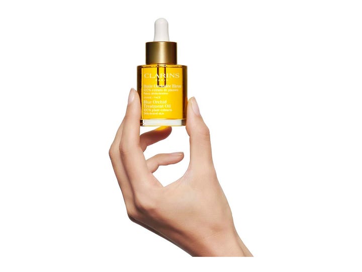 Clarins Blue Orchid Face Treatment Oil 30 ml kosteuttava kasvoöljy kultakorkkisessa lasipullossa kädessä.