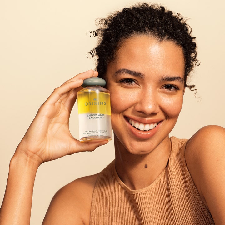 Origins Checks & Balances Milky Oil Cleanser 150 ml puhdistusöljy meikinpoistoon kaksifaasinen pullo naisen kädessä