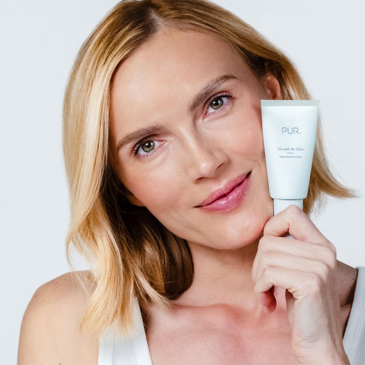 PÜR Go With The Glow Niacinamide Drops 30 ml heleyttävä seerumi vaaleassa tuubissa mallin kasvojen vierellä.