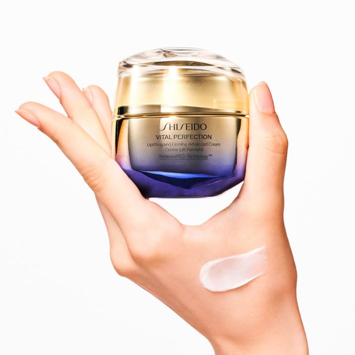 Shiseido Vital Perfection Advanced Day Cream 50 ml kiinteyttävä päivävoide kultaisessa purkissa ja voidenäyte kädellä