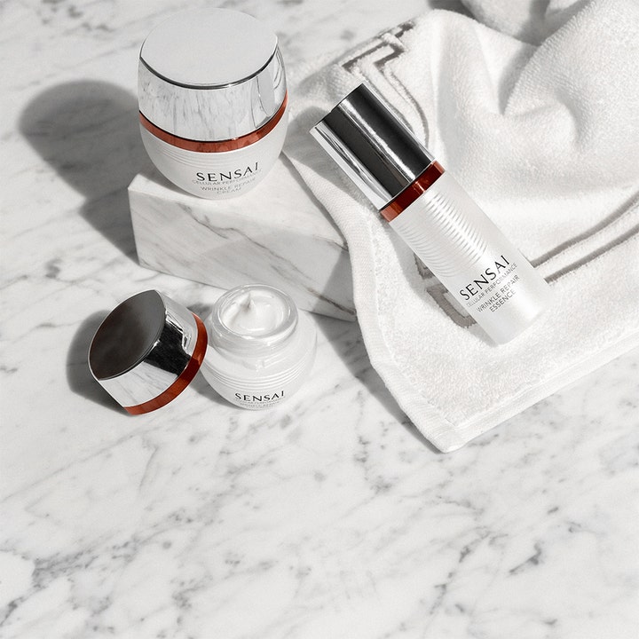 Sensai Cellular Performance Wrinkle Repair Essence 40 ml silottava hoitoneste valkoisessa pumpussa marmorialustalla.
