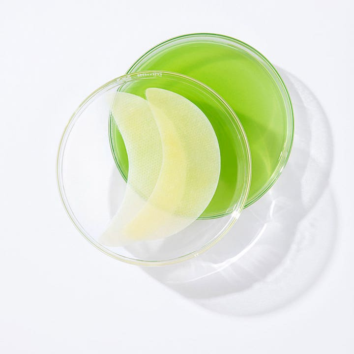Murad Retinol Youth Renewal Eye Mask 5 kpl silmänympärysnaamiot lasisessa maljassa vihreän nesteen päällä.