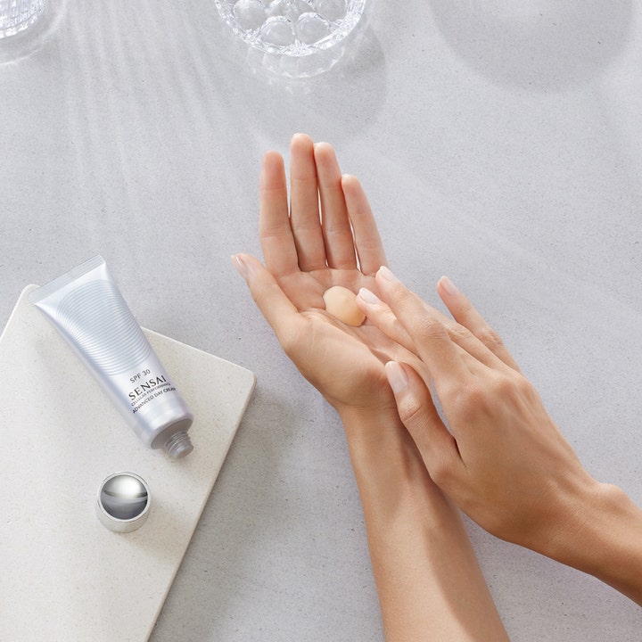 Sensai Cellular Performance Advanced Day Cream SPF30 50 ml suojaava päivävoide hopeisessa tuubissa ja voidetta kämmenellä