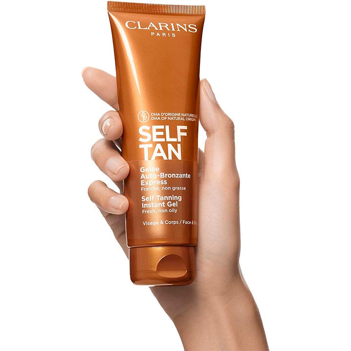 Clarins Self Tanning Instant Gel 125 ml itsetuskettava geeli vartalolle kädessä pidetyssä kuparinvärisessä tuubissa