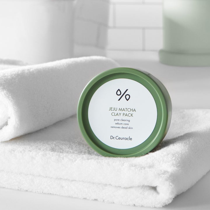 Dr. Ceuracle Jeju Matcha Clay Mask 115 g syväpuhdistava savinaamio vihreässä purkissa valkoisen pyyhkeen päällä.