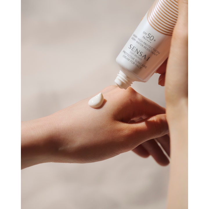 Sensai Silky Bronze Protective Cream Face SPF50+ 50 ml aurinkovoide kasvoille ja valkoinen voidepisara iholla