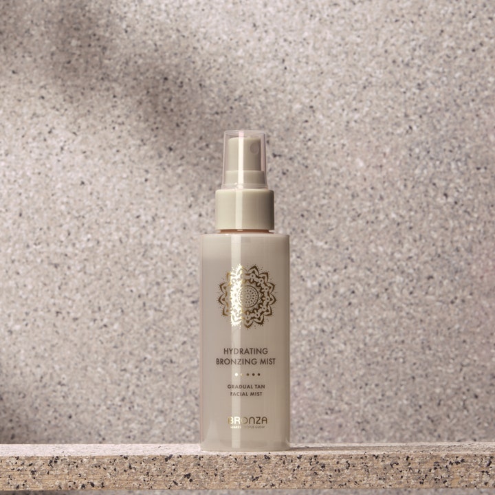 Bronza Hydrating Bronzing Mist Coconut 100 ml itseruskettava suihke kivisellä taustalla.