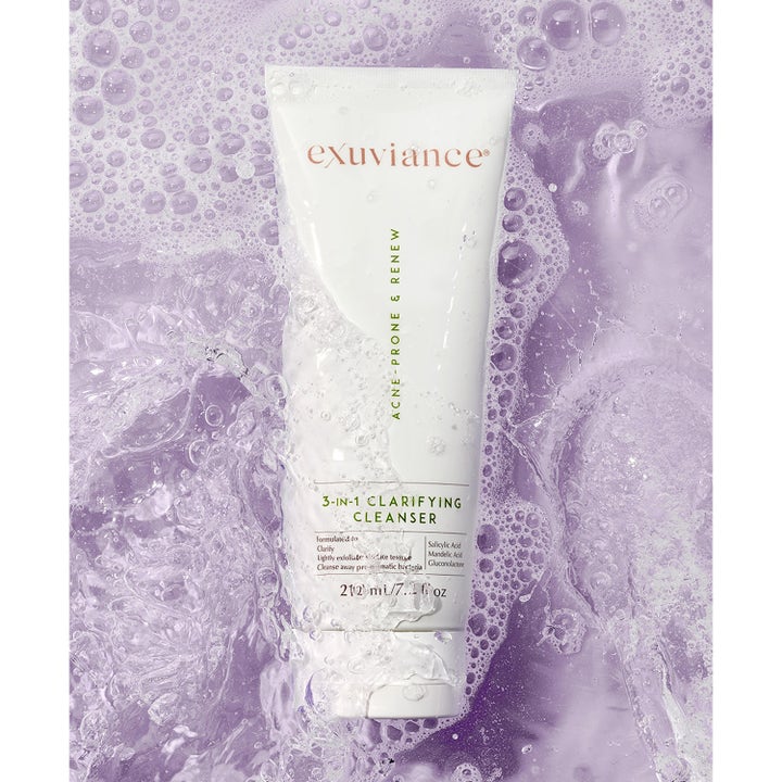 Exuviance 3-in-1 Clarifying Cleanser 212 ml syväpuhdistava kasvopesu valkoisessa tuubissa liilan kuplivan veden seassa.