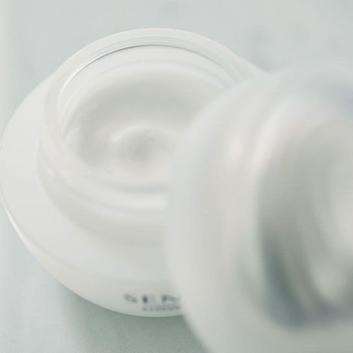 Sensai Comforting Barrier Mask 60 ml rauhoittava kasvonaamio, jonka täyteläinen valkoinen koostumus näkyy avatussa purkissa.