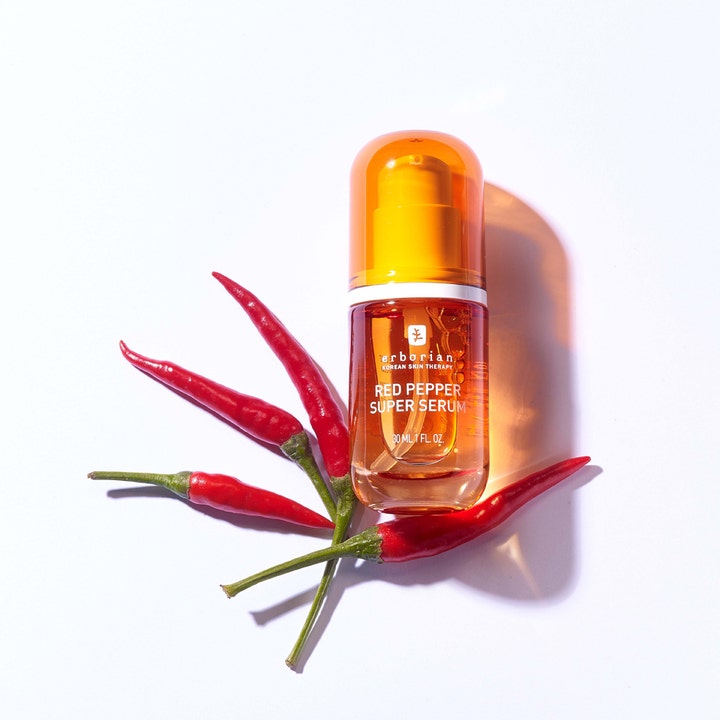 Erborian Red Pepper Super Serum 30 ml kirkastava kasvoseerumi oranssissa pullossa punaisten chilien päällä.