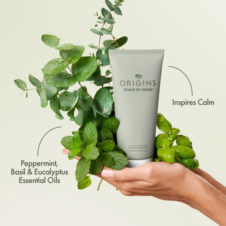 Origins Peace Of Mind 200 ml rauhoittava vartalokuorinta harmaassa tuubissa eukalyptuksen ja mintun ympäröimänä.