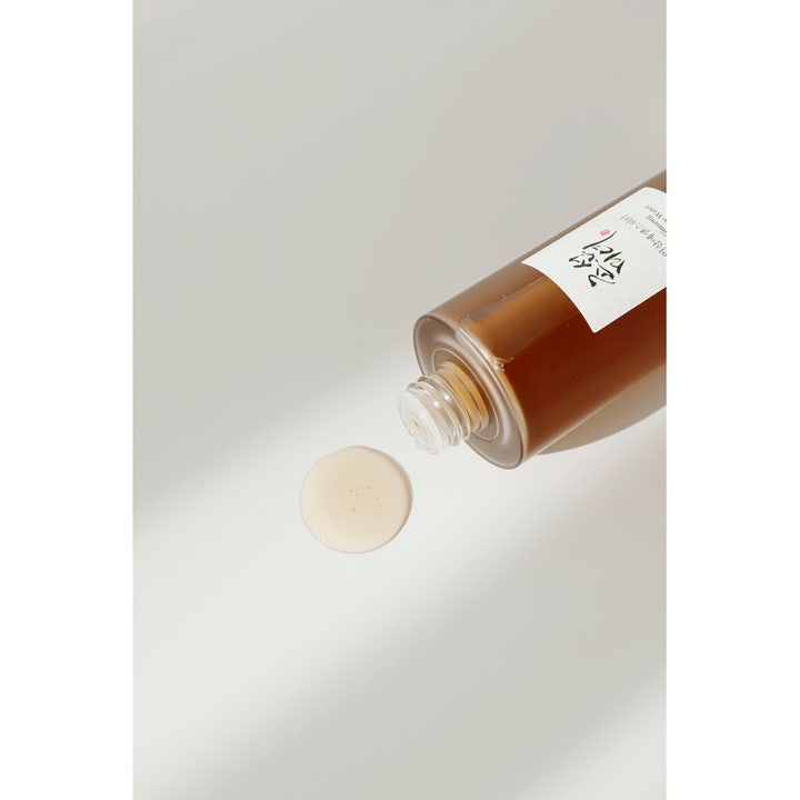 Beauty of Joseon Ginseng Essence Water heleyttävä hoitoneste ja pisara vaaleanruskeaa nestettä pullon vieressä