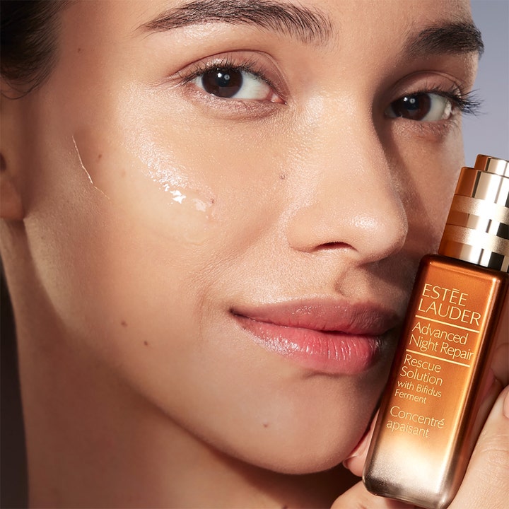Estée Lauder Advanced Night Repair Rescue Solution 20 ml rauhoittava seerumi naisen iholla ja ruskea lasipullo.