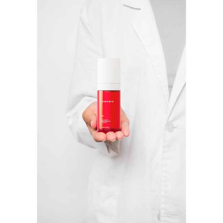 Niche Beauty Lab Theramid Azid 30 ml seerumi punaisessa pullossa valkoiseen työtakkiin pukeutuneen henkilön kämmenellä.