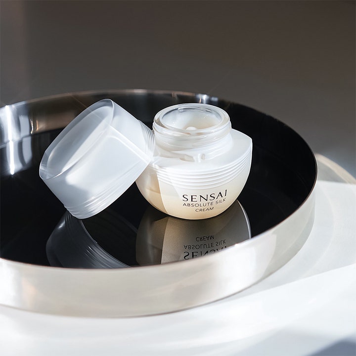 Sensai Absolute Silk Cream 40 ml kosteuttava kasvovoide avatussa valkoisessa purkissa heijastavalla tarjottimella.
