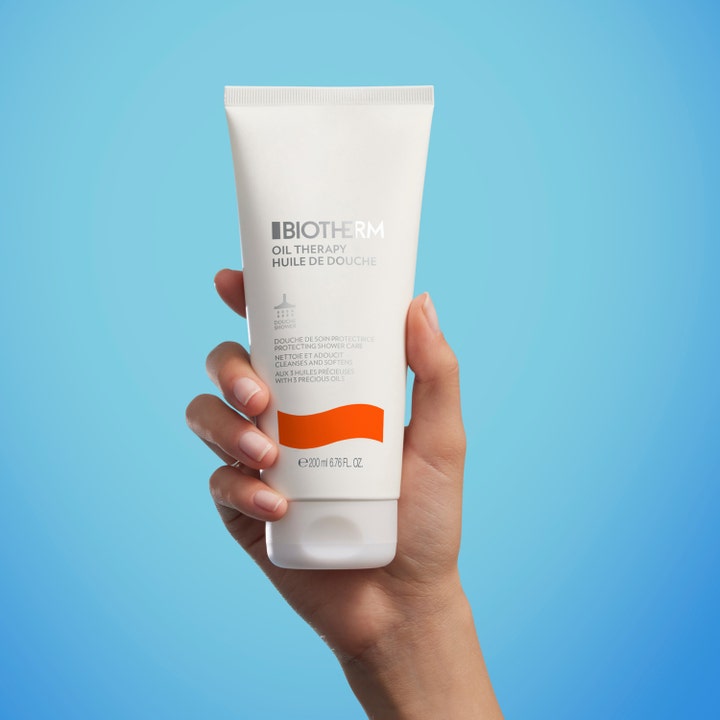 Biotherm Oil Therapy Baume Corps 200 ml kosteuttava suihkugeeli valkoisessa tuubissa kädessä pidettynä.
