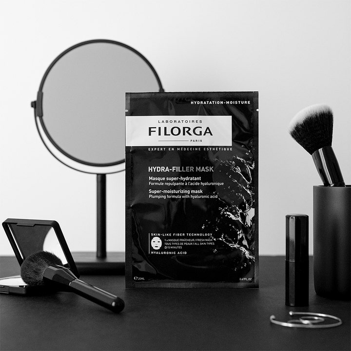 Filorga Hydra-Filler Mask 23 g kosteuttava kasvonaamio mustassa pakkauksessa meikkisiveltimien ja peilin ympäröimänä.