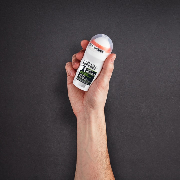 L'Oréal Paris Men Expert Deo Shirt Protect 50 ml roll-on-deodorantti miehen kädessä tummalla taustalla.