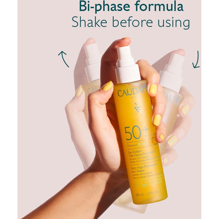 Caudalie Vinosun Very High Protection Water SPF50+ 150 ml aurinkosuoja kädessä jota ravistetaan