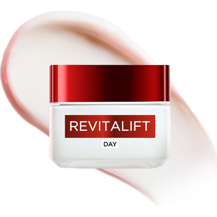 L'Oréal Paris Revitalift 50 ml kiinteyttävä päivävoide valkoisessa purkissa vaaleanpunaisen voide-swatchin edessä