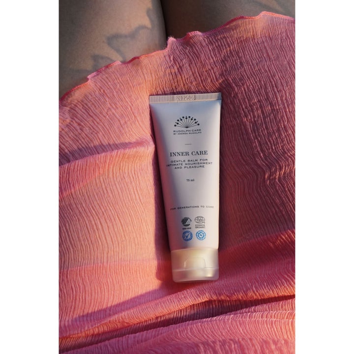 Rudolph Care Inner Care Body Balm 75 ml hoitava intiimivoide vaaleassa tuubissa vaaleanpunaisen kankaan päällä.