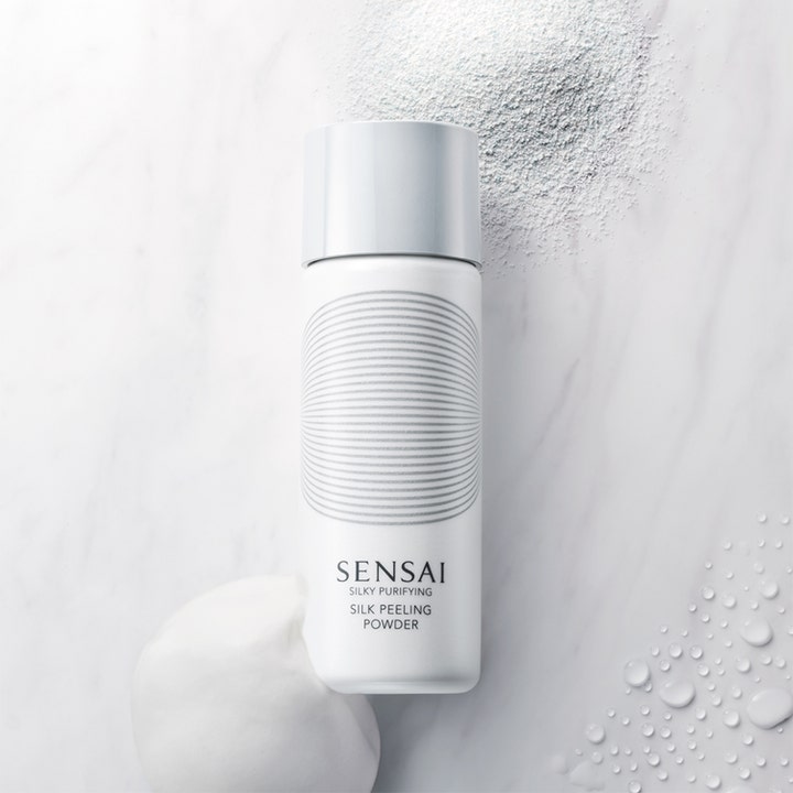 Sensai Silky Purifying Silk Peeling Powder 40 g kirkastava kuorinta valkoisessa pullossa jauheen ja vaahdon kera.
