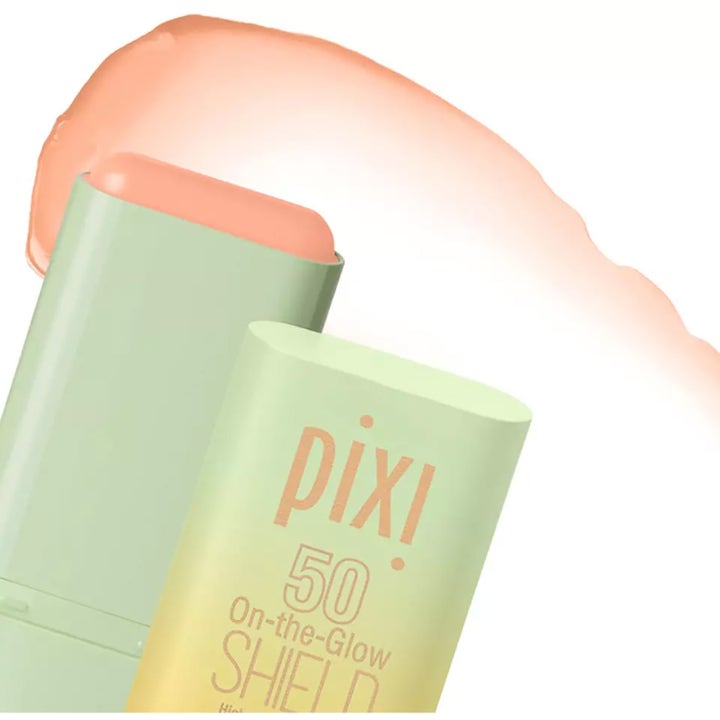 Pixi On-the-Glow Shield SPF 50 19 g suojaava aurinkosuojapuikko vihreässä hylsyssä ja persikkainen koostumus.