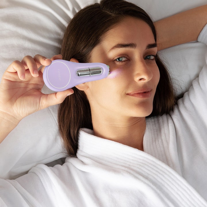 FOREO BEAR 2 eyes & lips 1 kpl kiinteyttävä kasvolaite nainen käyttää vaaleanviolettia laitetta silmänympäryksilleen