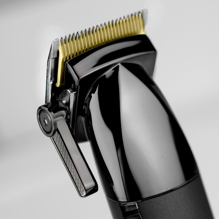 BaByliss Super X Metal Hair Clipper 1 kpl hiustenleikkuukone on kiiltävän musta ja siinä on kullanväriset terät.